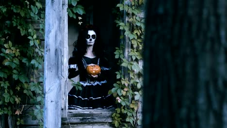 A-young-woman-with-halloween-make-up-holding-a-pumpkin-with-a-lighted-candle.-4K