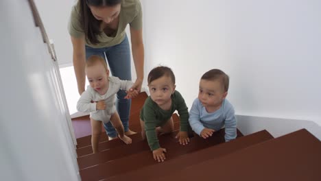 Asian-Toddler-Triplets-Crawling-up-Staircase,-and-Mom-Helping