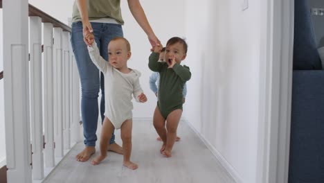 Unrecognizable-Woman-Leading-Asian-Baby-Triplets-by-Hand-at-Home