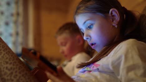 4K-little-boy-and-girl-sitting-with-tablet-PCs-in-hand-playing-video-games