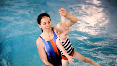 Schwimmbad.-Mama-bringt-einem-kleinen-Kind-das-Schwimmen-im-Pool-bei.