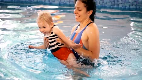 Schwimmbad.-Mama-bringt-einem-kleinen-Kind-das-Schwimmen-im-Pool-bei.