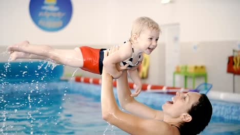 Schwimmbad.-Mama-bringt-einem-kleinen-Kind-das-Schwimmen-im-Pool-bei.