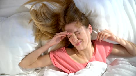 Unhappy-sleepy-young-woman-does-not-want-to-wake-up-in-the-morning-and-hiding-under-the-blanket