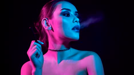 Hermosa-mujer-morena-fumar-cigarrillo-electrónico-en-luz-de-neón-color