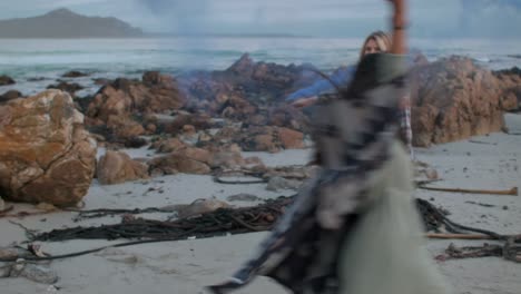 Two-young-women-with-colour-smoke-grenades-on-the-beach