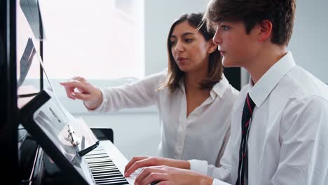 Männliche-Schüler-mit-Lehrer-im-Musikunterricht-Klavier-zu-spielen