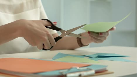 Woman-is-cutting-green-paper-using-scissors