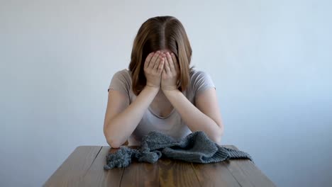 Young-woman-crying-over-grey-knitting