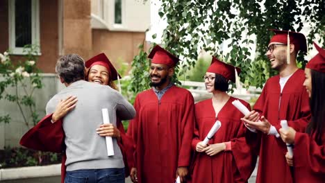 Friendly-proud-professor-is-hugging-glad-African-American-girl-student-and-shaking-her-hand-then-wishes-good-luck-to-mulninational-group-of-students.