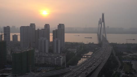 Wuhan,-China,-Dunst-Wetter,-Sonnenuntergang-am-Fluss-Städte,-hohe-Gebäude,-eine-Brücke,-Boote-auf-dem-Fluss