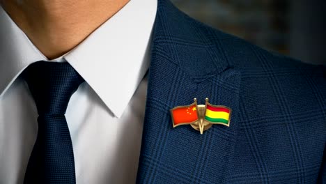 Businessman-Walking-Towards-Camera-With-Friend-Country-Flags-Pin-China---Bolivia