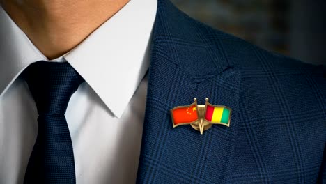 Geschäftsmann-zu-Fuß-in-Richtung-Kamera-mit-Freund-Land-Flaggen-Pin-China---Guinea