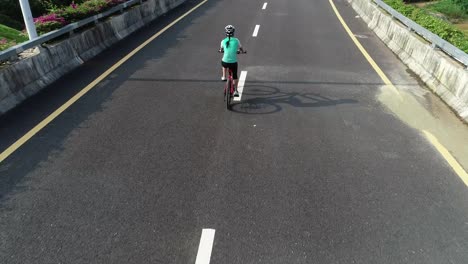 Aerial-view-of-experienced-woman-hands-free-cycling-riding-bike-on-highway-road