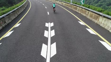 Aerial-view-of-experienced-woman-hands-free-cycling-riding-bike-on-highway-road