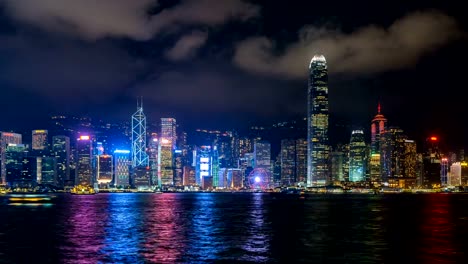 Lapso-de-tiempo-de-los-rascacielos-y-barco-flotante-en-el-puerto-de-Victoria,-Hong-Kong-de-noche.-4K