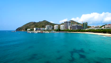 Bau-eines-Hotels-am-Fuße-des-Berges-an-der-Küste-von-türkisfarbenem-Meer-Luftblick