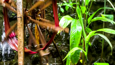 Bamboo-water-wheel-used-for-irrigation,-brings-water-from-stream-to-plantation.-Close-up-of-bamboo-wheel-delivering-water.-Asia
