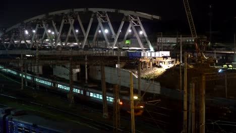 La-construcción-de-un-puente-de-acero-y-movimiento-de-la-noche-de-los-trenes-en-un-cruce-de-ferrocarril