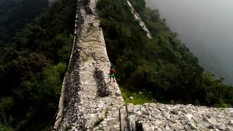 Luftaufnahme-des-jungen-Fitness-Frau-Trailläufer-läuft-oben-auf-der-Mauer