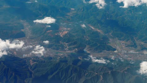 Beautiful-view-through-airplane-window,-airplane-flying-above-city-in-mountains