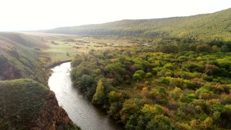 Aerial-Drone-Footage-View:-Flight-over-autumn-mountains-and-small-river-with-forests-in-sunrise-soft-light.-Majestic-landscape.