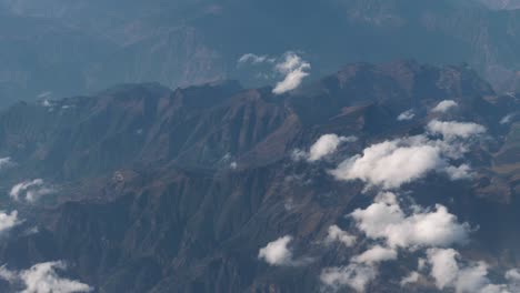 Beautiful-view-through-airplane-window,-airplane-flying-above-city-in-mountains