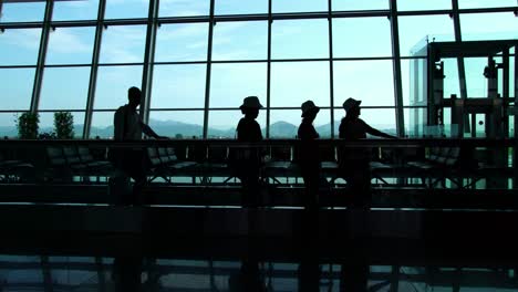 Silhouette-der-Passagiere-zu-Fuß-mit-Gepäck-in-einer-geschäftigen-Flughafen-terminal