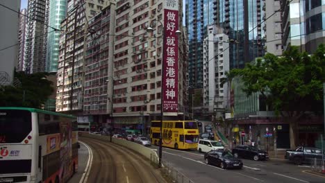 Iconic-double-decker-city-tram-and-bus-passing-on-the-street-of-downtown-city-Hong-Kong,-China-in-Asia