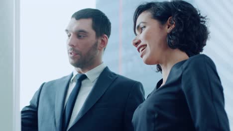 In-the-Office-Handsome-Businessman-and-Beautiful-Businesswoman-Have-Discussion-while-Drawing-on-Whiteboard.-Planning-Marking-Expansion,-Consulting-Data-and-Making-Graphs.-Modern-Stylish-People.