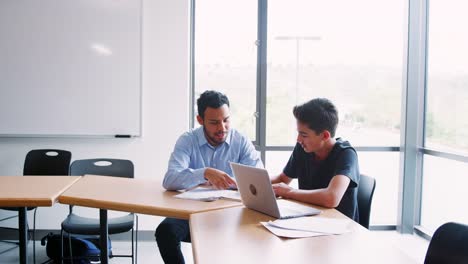 High-School-Tutor-Giving-Male-Student-One-To-One-Tuition-At-Desk