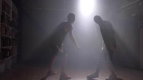 Player-trying-to-take-ball-from-another-player-in-room-with-smoke-and-floodlight