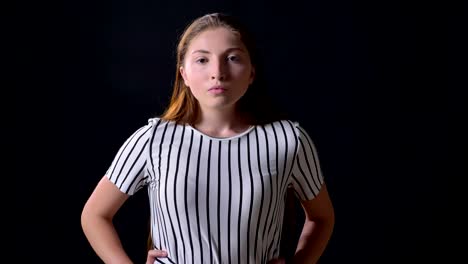 Angry-young-beautiful-woman-looking-at-camera-with-serious-expression-and-standing-isolated-on-black-background