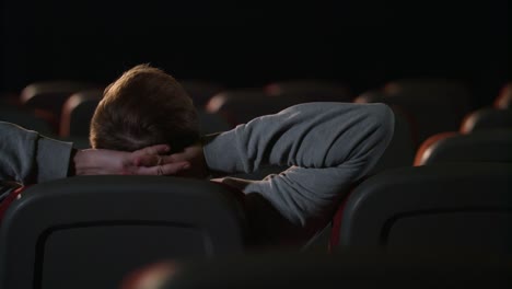 One-man-sitting-in-empty-cinema-hall.-Young-man-relaxing-in-empty-dark-theatre