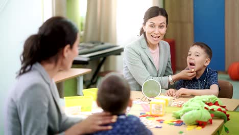 Süße-junge-und-Frau-Logopädin-arbeiten-zusammen-in-Therapiesitzung