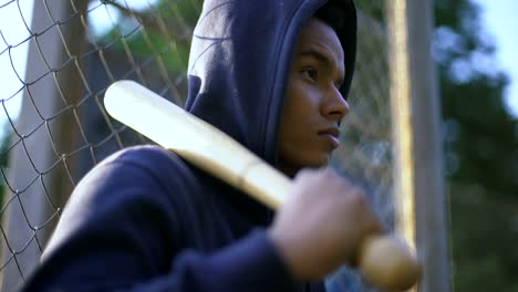 Afro-american-teenager-holding-baseball-bat,-youth-gang-in-ghetto,-closeup