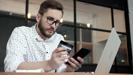 Hombre-hacer-pago-en-línea-teléfono-Banco-con-tarjeta-de-crédito