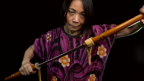 old-asian-woman-pulling-vintage-sword-from-sheath