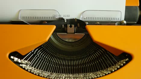 High-angle-shot-of-a-person-writing-CRIME-SCENE-on-an-old-typewriter,-with-sound