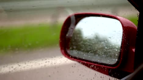 close-up,-Wassertropfen-auf-Seitenfenster-des-Autos-während-der-Fahrt.-Vom-starken-Wind-fließen-Tröpfchen-das-Glas-nicht-ab,-sondern-nach-oben.-durch-Fenster-sehen-Sie-Seite-Rückspiegel