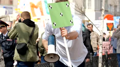 A-man-smiles-and-cheerfully-speaks-in-a-megaphone-or-loudspeaker-at-a-meeting.