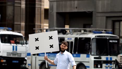 Aggressive-rebel-look-camera-at-the-revolution-and-holds-a-poster-in-his-hand.