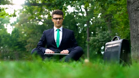 Hombre-de-negocios-sentado-en-la-hierba-en-el-bosque-y-meditar-después-de-día-del-trabajador