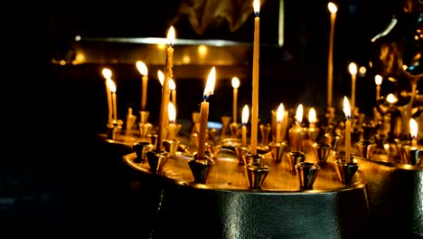 Frau-zündet-eine-Wachskerze-in-eine-Pfanne-in-einem-orthodoxen-katholischen-alten-Tempel