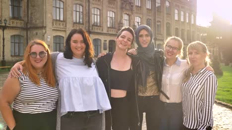 diverse-group-of-laughing-caucasian-girls-standing-near-and-holding-with-proud-outside-in-daytime