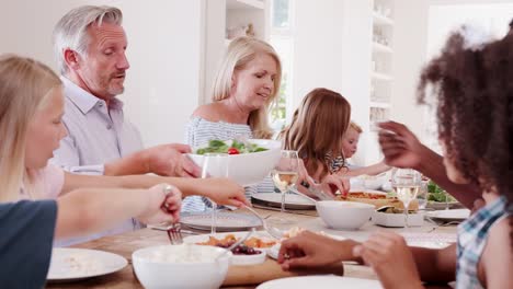 Mehr-Generationen-Familie-Gnade-vor-Mahlzeit-an-Tisch-zu-Hause-sitzen-und-sagen