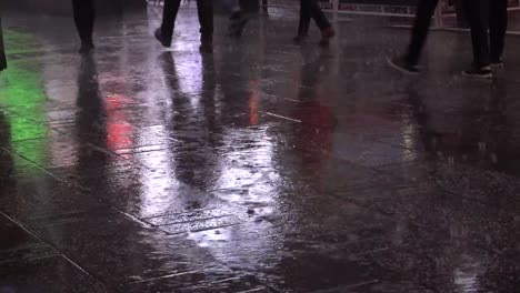 People-walking-at-night-on-a-sidewalk-during-a-rainy-day.