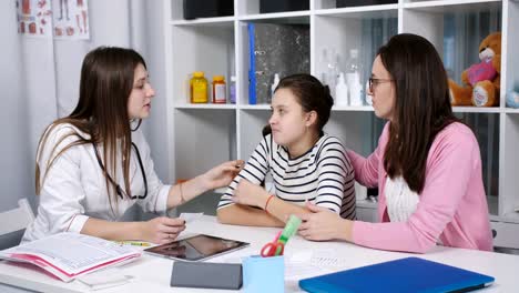 Advice-in-the-doctor's-office.-A-mother-and-daughter-a-teenager-on-the-medical-examination.-A-doctor-examines-a-sore-throat,-the-girl-of-the-patient.