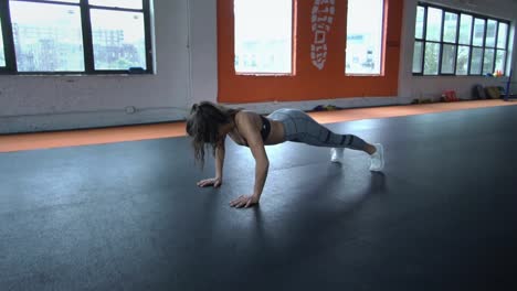 Young-multi-ethnic-hispanic-athletic-healthy-woman-doing-push-ups-in-gym-strength-training-in-fitness-gym.-Shot-in-slow-motion.