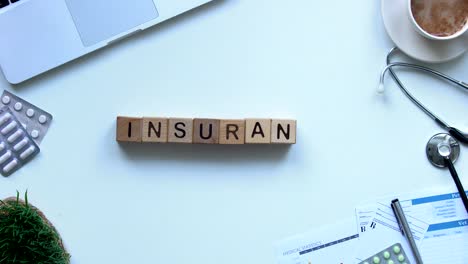 Insurance-word-on-wooden-cubes-made-by-doctors-hand,-health-and-life,-top-view